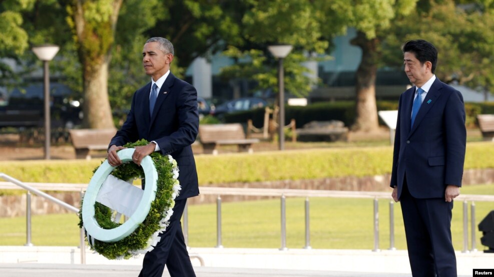 FILE - U.S. President Barack Obama, left, with Japanese Prime Minister Shinzo Abe, prepares to lay a wreath at Japan's Hiroshima Peace Memorial Park, May 27, 2016. Abe will reciprocate by visiting Pearl Harbor, Hawaii, in late December. 