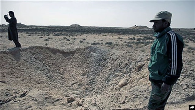 Libyan men survey a hole that defected soldiers say was created by an air strike impact the previous week by the Libyan army in the eastern town of Ajdabiya, Libya, on March 1, 2011