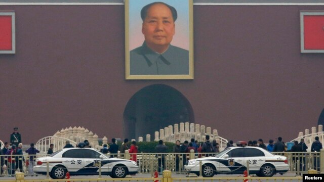 Xe cảnh sát đậu phía trước bức chân dung khổng lồ của Mao Trạch Đông tại lối vào chính của Tử Cấm Thành ở Bắc Kinh.