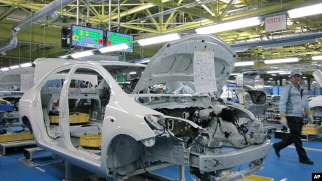 A worker walks past a Toyota Motor Yaris sedan at Central Motor Co's new factory in Ohira village, Japan, April 16, 2011