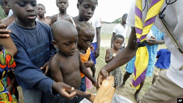 A man distributes bread to children at Abidjan's St. Ambrose church, a temporary refuge for people who fled from clashes between forces loyal to incumbent president Laurent Gbagbo and his rival Alassane Ouattara (File)