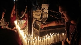 Exiled Tibetans light candles in front of portraits of 21-year-old monk Phuntsog, during a candlelit vigil to honor the monk who set himself on fire in an anti-government protest, in Dharmsala, India, March 17, 2011