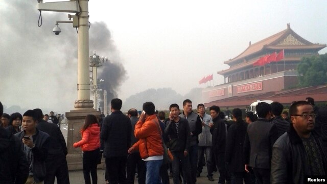 Người đi bộ dọc Đại lộ Trường An trong lúc khói bốc lên từ vụ cháy xe tại Quảng trường Thiên An Môn, gần cổng chính để vào Tử Cấm Thành tại Bắc Kinh, ngày 28/10/2013