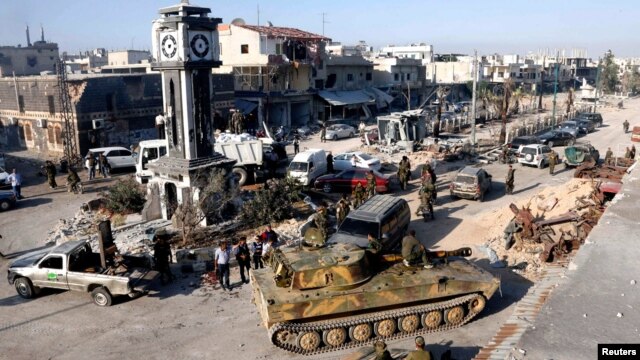 Tentara yang loyal pada rezim Suriah dengan tank-tank militer mereka di Qusair, setelah angkatan darat Suriah mengambil alih kota itu dari pemberontak (5/6). (Reuters/Mohamed Azakir)