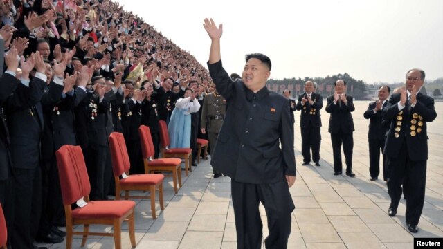 Lãnh đạo Bắc Triều Tiên Kim Jong-Un vẫy chào khi ông đến chụp ảnh với các giới chức, nghệ sĩ, và nhân viên của 1 studio ở Bình Nhưỡng, 19/4/2012