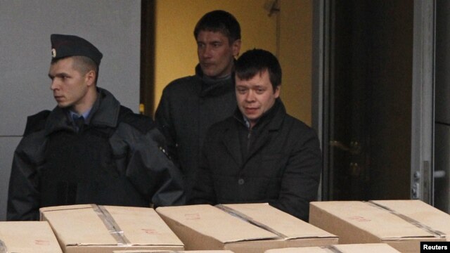 Detained opposition activist Konstantin Lebedev (R, front) is escorted out of a building of the Russian Investigative Committee in Moscow, October 17, 2012.