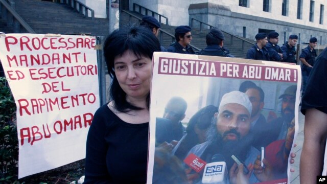 A protester holds up a poster with writing reading in Italian "Justice for Abu Omar" above a picture of Muslim cleric Osama Moustafa Hassan Nasr, also known as Abu Omar, outside Milan's court house while the trial of 26 Americans and seven Italians accused of orchestrating a CIA-led kidnapping of an Egyptian terror suspect Nasr was taking place inside the courtroom, in Milan, Italy, Sept. 23, 2009.