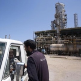 A Libyan worker chats with two rebels in a vehicle as they patrol an oil refinery controlled by anti Gadhafi forces on the western outskirt of Zawiya city, August 19, 2011
