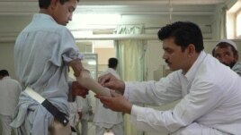 An Afghan technician helps a young amputee adjust his prosthetic arm at one of the International Committee of the Red Cross (ICRC) hospitals for war victims and the disabled in Jalalabad on June 26, 2012.