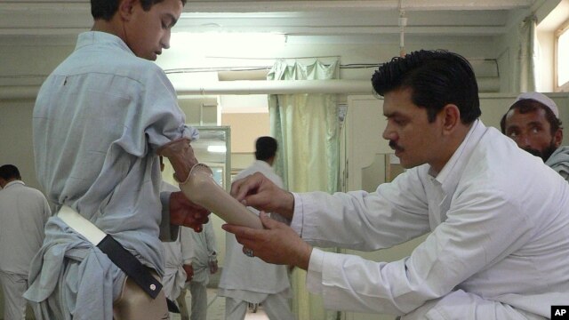 An Afghan technician helps a young amputee adjust his prosthetic arm at one of the International Committee of the Red Cross (ICRC) hospitals for war victims and the disabled in Jalalabad on June 26, 2012.