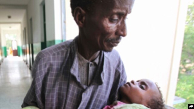 An man carries his malnourished child through the corridors inside Banadir hospital in Somalia's capital Mogadishu.  (File Photo)