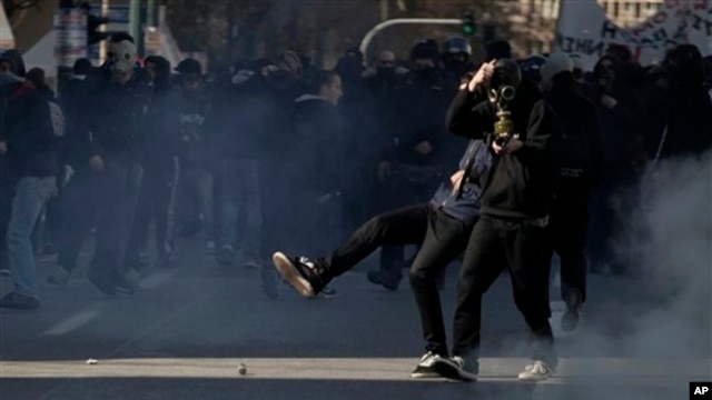 Protester kicks tear-gas canister toward riot police during minor clashes at a protest of the 24-hour strike in Athens, Feb. 20, 2013.