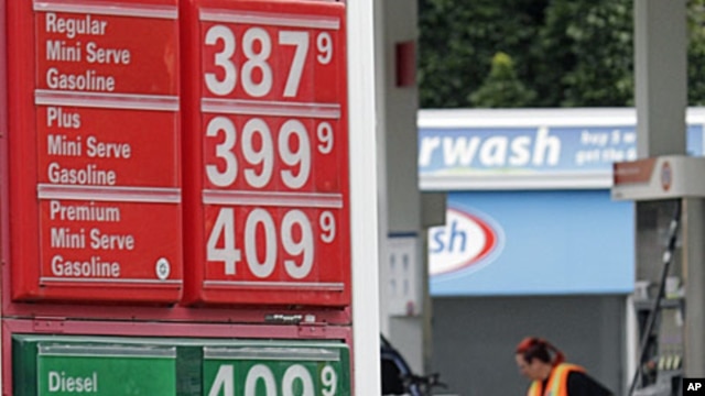 Prices are shown as Jaqueline Henderson pumps gas at a station in Portland, Ore., Friday, July 29, 2011