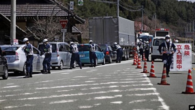 Police officers stop cars at a checkpoint near the town of Namie, Fukushima Prefecture, northeastern Japan, April 21, 2011