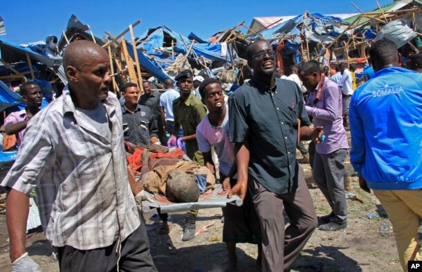 Somali men retrieve the dead body of a person who was killed when a car bomb targeted a police station in the Waberi neighborhood, where President Hassan Sheikh Mohamud was visiting a university, in the capital Mogadishu, Saturday, Nov. 26, 2016.