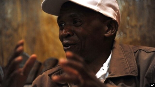 Burundi's main opposition leader Agathon Rwasa sits underneath the portrait of Burundian President Pierre Nkurunziza during an interview with journalists in the south western Burundian town of Rumonge, 12 May 2010
