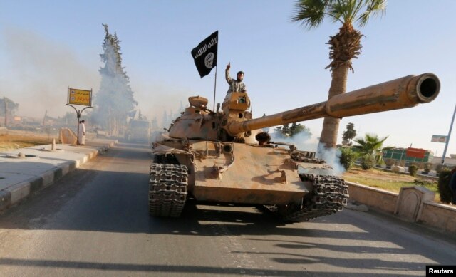 FILE - Militant Islamist fighters on a tank take part in a military parade along the streets of northern Raqqa province, June 30, 2014.