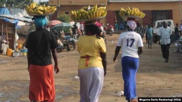 Faridah Hussein (No. 17 T-shirt on right) carries bananas into a market in Juba. The 33-year-old mother of three doesn't put the 15-20 South Sudanese pounds she makes a day by selling the bananas in a bank because she thinks she earns too little to open an account.