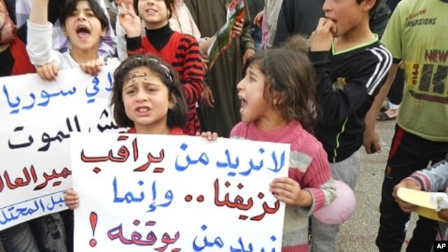 Demonstrators take part in a protest against Syria's President Bashar Al-Assad in Kafranbel, near Idlib May 1, 2012. Poster reads: "No need to observe our bleeding..we want who can stop it". 