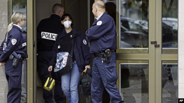French police officers stand guard at the entrance of a building in Strasbourg, France, Saturday Oct. 6, 2012, where  a suspect was shot dead after firing at police.