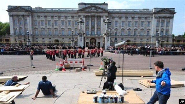 A TV crew works as members of the household brigade marching band walk in front of Buckingham palace, in London, on April 28, 2011.