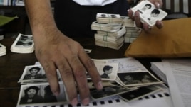 In this photo taken on Aug. 20, 2012, Director of Documentation Center of Cambodia, Youk Chhang arranges photos, a part of about a thousand of newly-discovered photo collection of detainees at the former Khmer Rouge main prison S-21, in his office in Phno