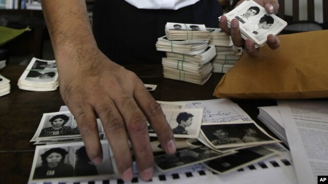 In this photo taken on Aug. 20, 2012, Director of Documentation Center of Cambodia, Youk Chhang arranges photos, a part of about a thousand of newly-discovered photo collection of detainees at the former Khmer Rouge main prison S-21, in his office in Phno