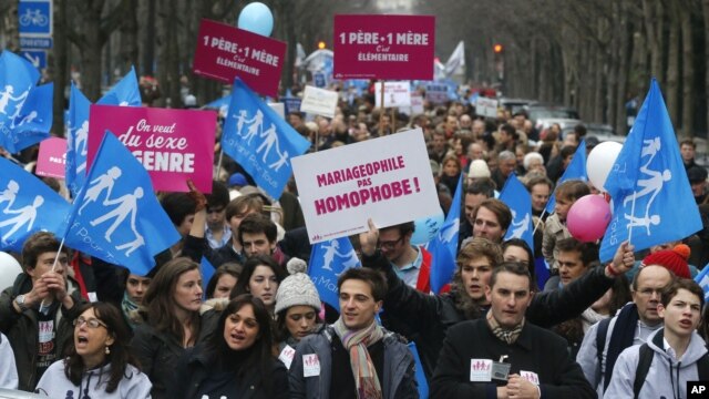 People demonstrate with red signs reading 'One father, one mother, it's obvious,' in Paris, Sunday, January 13, 2013. 
