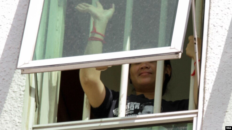 Tep Vanny waves her hand from a window at Phnom Penh Municipal Court as she is being questioned by the court over the Black Monday campaign, Phnom Penh, Cambodia, Wednesday, August 17, 2016. ( Leng Len/VOA Khmer) ​​​​