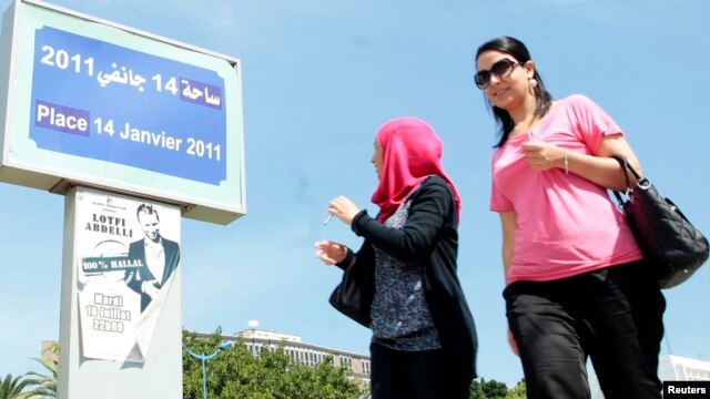 Women walk past a poster of the play ?Made in Tunisia, 100 percent halal? by Tunisian actor, playwright Lotfi Abdeli. The play was boycotted previously by hundreds of Salafi Muslims who believed the show was offensive to Islam, (File Photo).