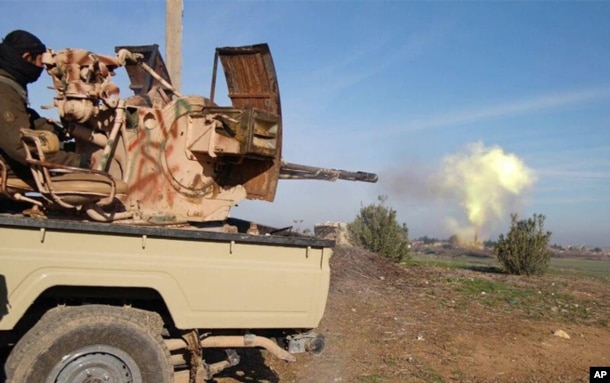 FILE - In this image posted on a militant social media account by the Al-Baraka division of the Islamic State group Feb. 24, 2015, a fighter fires a heavy weapon mounted on the back of a pickup truck during fighting in Tal Tamr, Syria.