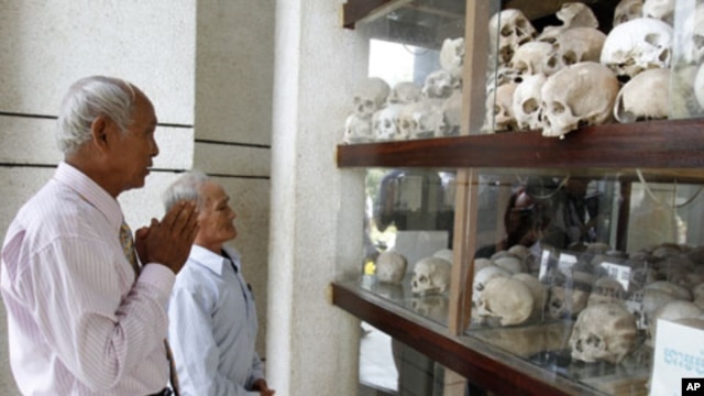 Survivors of the Khmer Rouge regime, Chum Mey (L) and Bou Meng (C) pray at Choeung Ek "Killing Fields" site located on the outskirts of Phnom Penh, June 25, 2011