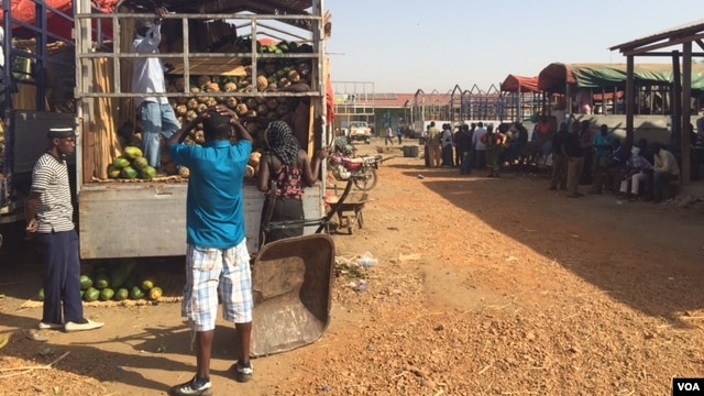 Workers offload fruit trucks from Uganda at Juba's Gumbo Market on March 10, 2015. Business owners are feeling the pressure as the strength of the South Sudanese pound weakens. (Photo: G. Joselow / VOA)