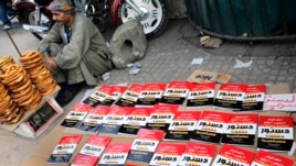 An Egyptian pritzel vender sits next to copies of the new constitution sold on a street in Cairo, Egypt, Saturday, Dec. 28, 2013.