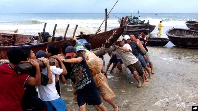 Ngư dân tỉnh Quảng Nam đẩy một tàu đánh cá vào bờ. Tàu bè các tỉnh duyên hải từ miền Trung trở ra đã được khuyến cáo trở lại đất liền.