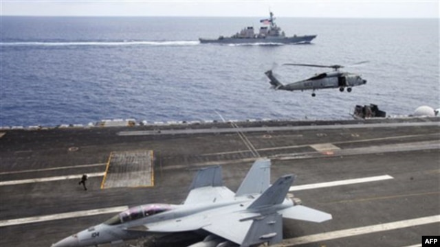 Máy bay chiến đấu F/A-18F Super Hornet và trực thăng SH-60 Seahawk của hải quân Mỹ trên tàu sân bay USS George Washington, phía sau là tàu khu trục USS John S. McCain (DDG-56) ngoài khơi bờ biển Việt Nam, ngày 13/8/2011