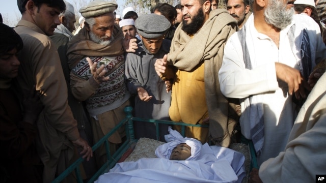 Villagers look at the body of health worker Hilal Khan, who was killed by gunmen in Wahidgari, outside of Peshawar, Pakistan, Dec. 20, 2012. 