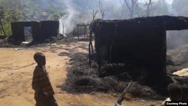 Two children walk by still smoldering houses in the village of Chukudum, where South Sudanese soldiers went on a deadly rampage on Tuesday, Oct. 7, 2014.