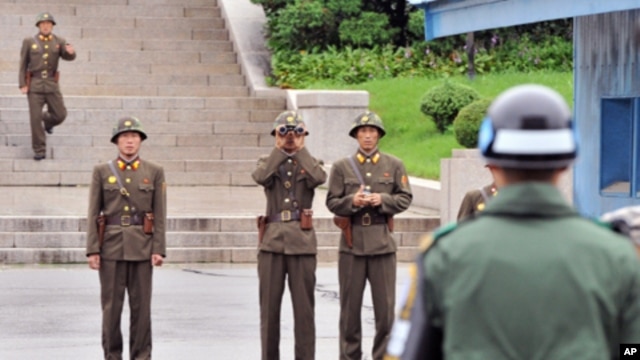 North Korean soldiers look towards the south as a South Korean soldier (R) stands guard in the demilitarized zone separating the two Koreas, July 15, 2011.