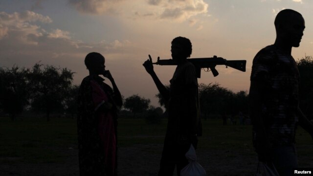 FILE - An armed man and a woman talk in Yuai Uror County, South Sudan, July 24, 2013. Tensions remain high after President Salva Kiir issued a decree last November splitting South Sudan's 10 states into 28, including the newly created states of Terkeka and Jubek.