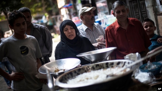 FILE - An Egyptian woman waits for her breakfast on a street fast food restaurant in Suleiman Gohar market in Dokki district in Cairo, Egypt. 