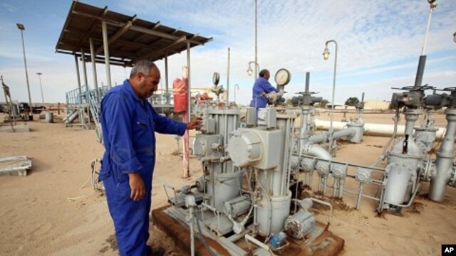 Workers check pipes and valves at Amaal oil field in eastern Libya, October 7, 2011.