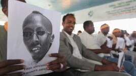 A Somali journalist holds a poster bearing the image of Abdiaziz Abdinur in Mogadishu in this January 27, 2013, file photo..