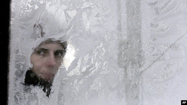 A woman looks through an icy window in a bus in Ukraine's capital, Kyiv, February 3, 2012.