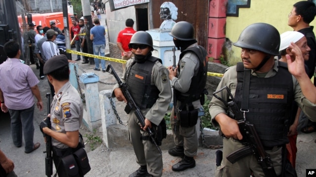 Indonesian police officers stand guard outside a building after a raid in Solo, Central Java, Indonesia, Saturday, Oct. 27, 2012.