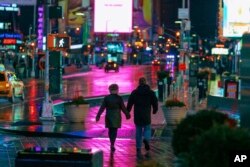 Una pareja camina por Times Square, Nueva York, al amanecer del domingo 19 de enero de 2019. El Servicio Nacional de Meteorología advirtió el sábado de una dramática baja en la te temperatura que podía convertir la lluvia del fin de semana en hielo antes del lunes.