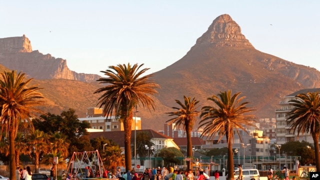 People enjoy the sunset with Table Mountain, left, and Lions Head, right, in Cape Town, South Africa.