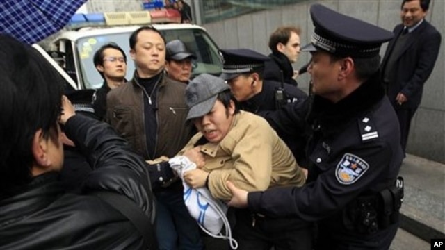 A man, center, is detained by police officers near the planned protest site is located at in Shanghai, China, February 27, 2011