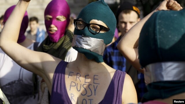Aktivisti s maskama pružaju podršku bendu "Pusi rajot" na demostracijama u Varšavi