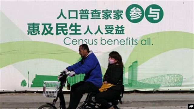 A man and woman ride an electric bicycle past a publicity board China's census in Beijing, 1 Nov. 2010. China kicked off its once-a-decade census on Monday, a whirlwind 10-day head count.